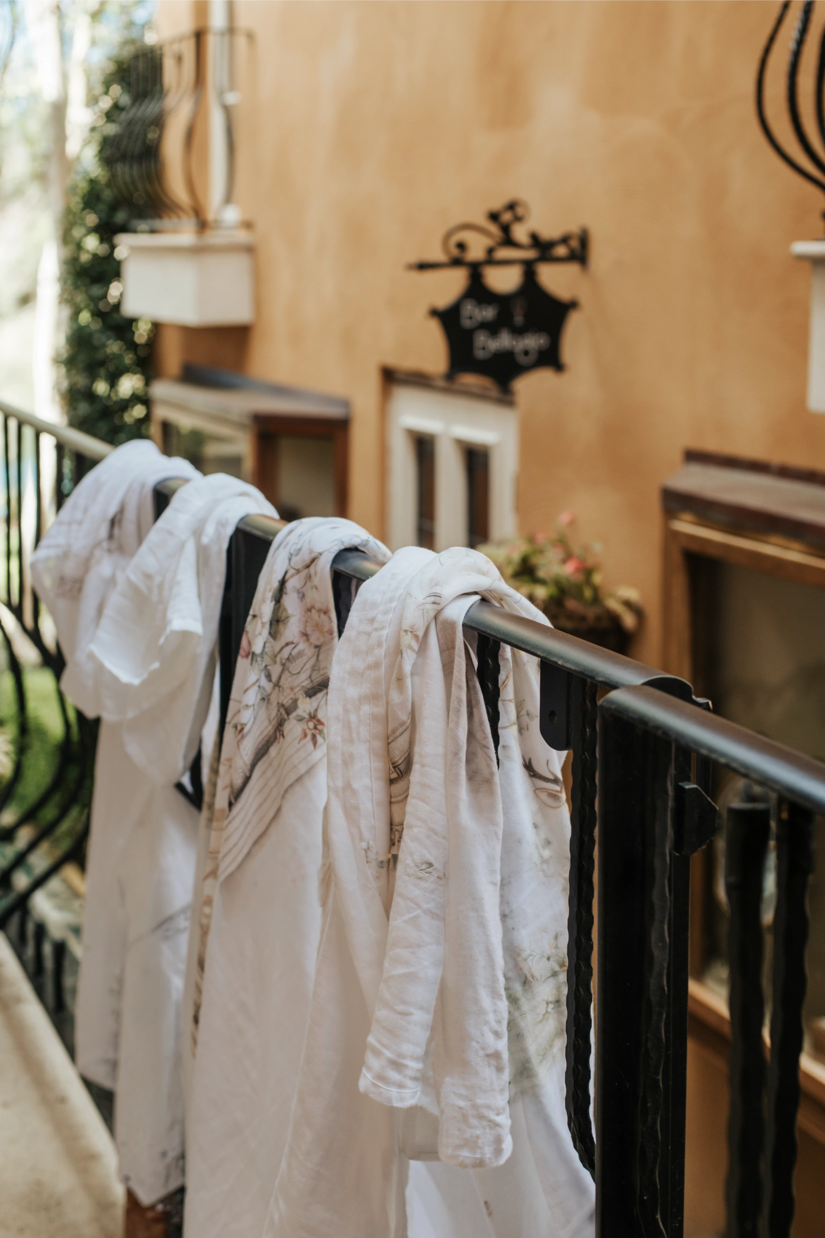 Several Fenne wrap prints hung to dry on an outdoor railing, showing different original designs