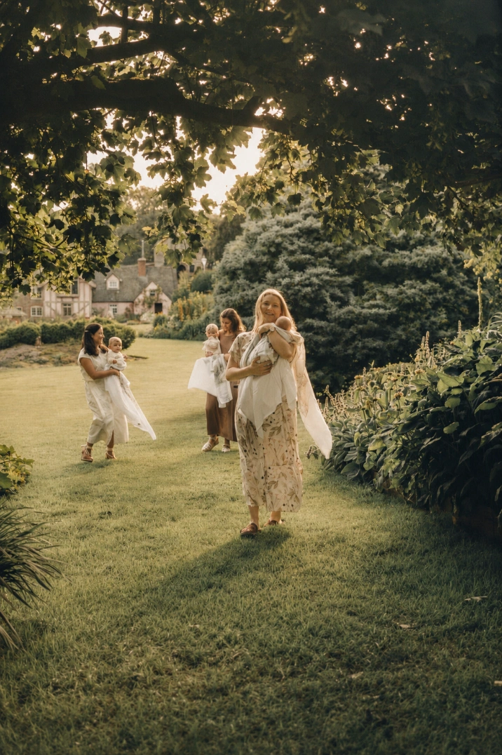 Three mothers walking through a garden, each carrying their baby in a Fenne wrap