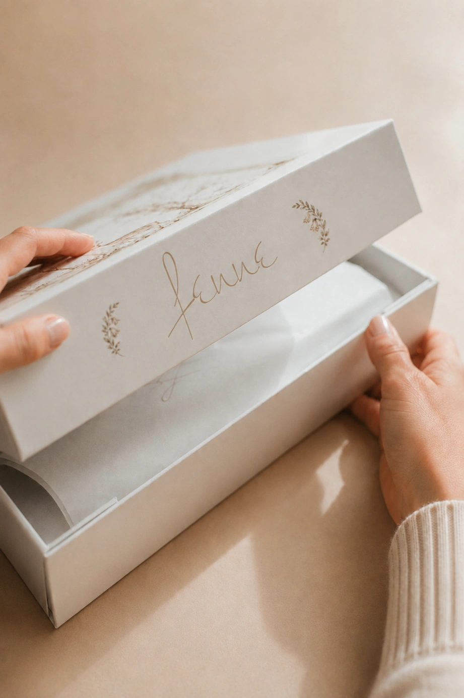 Hands opening a Fenne gift box lined with tissue paper