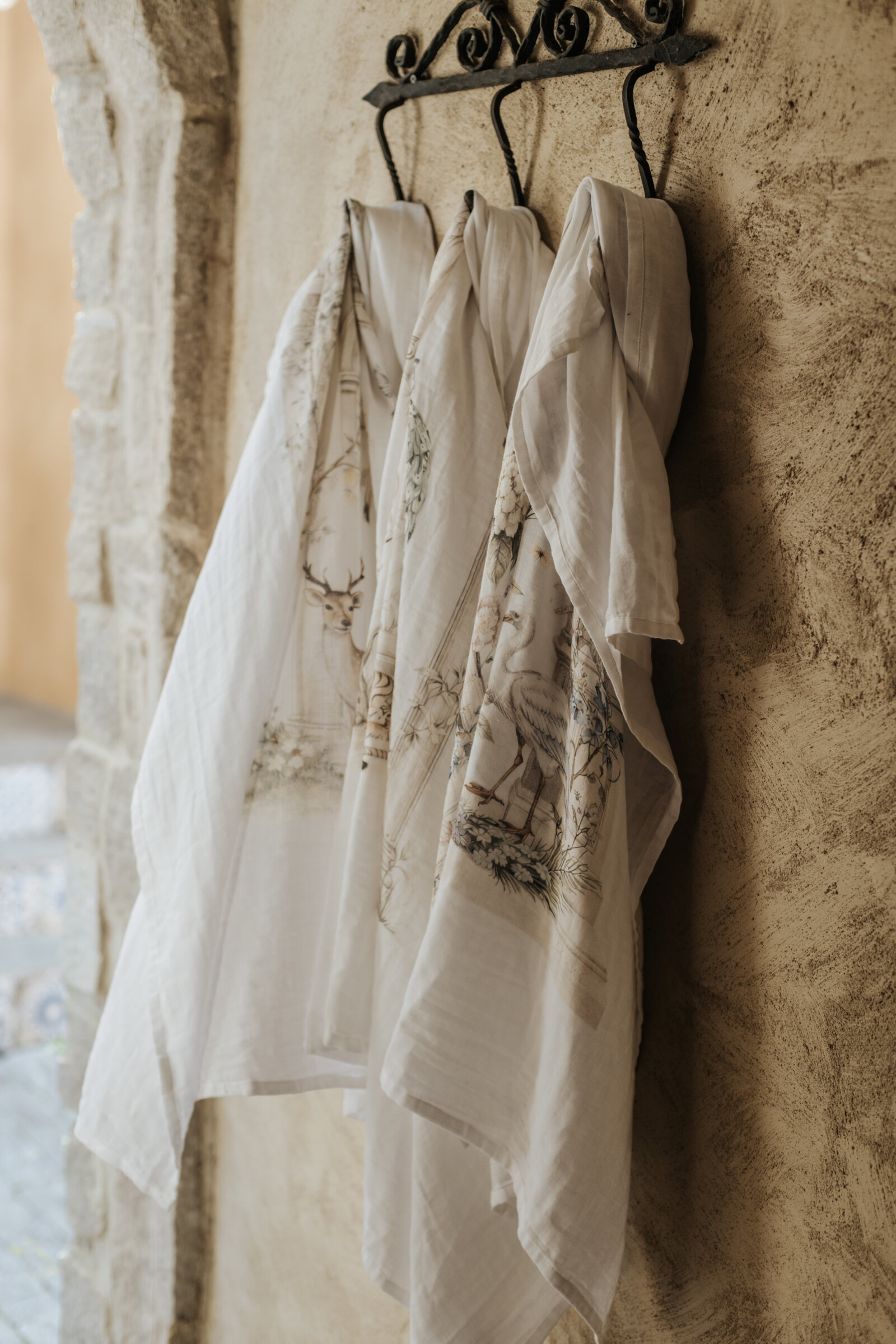 Fenne baby wraps hanging from a wall hook against a plaster wall